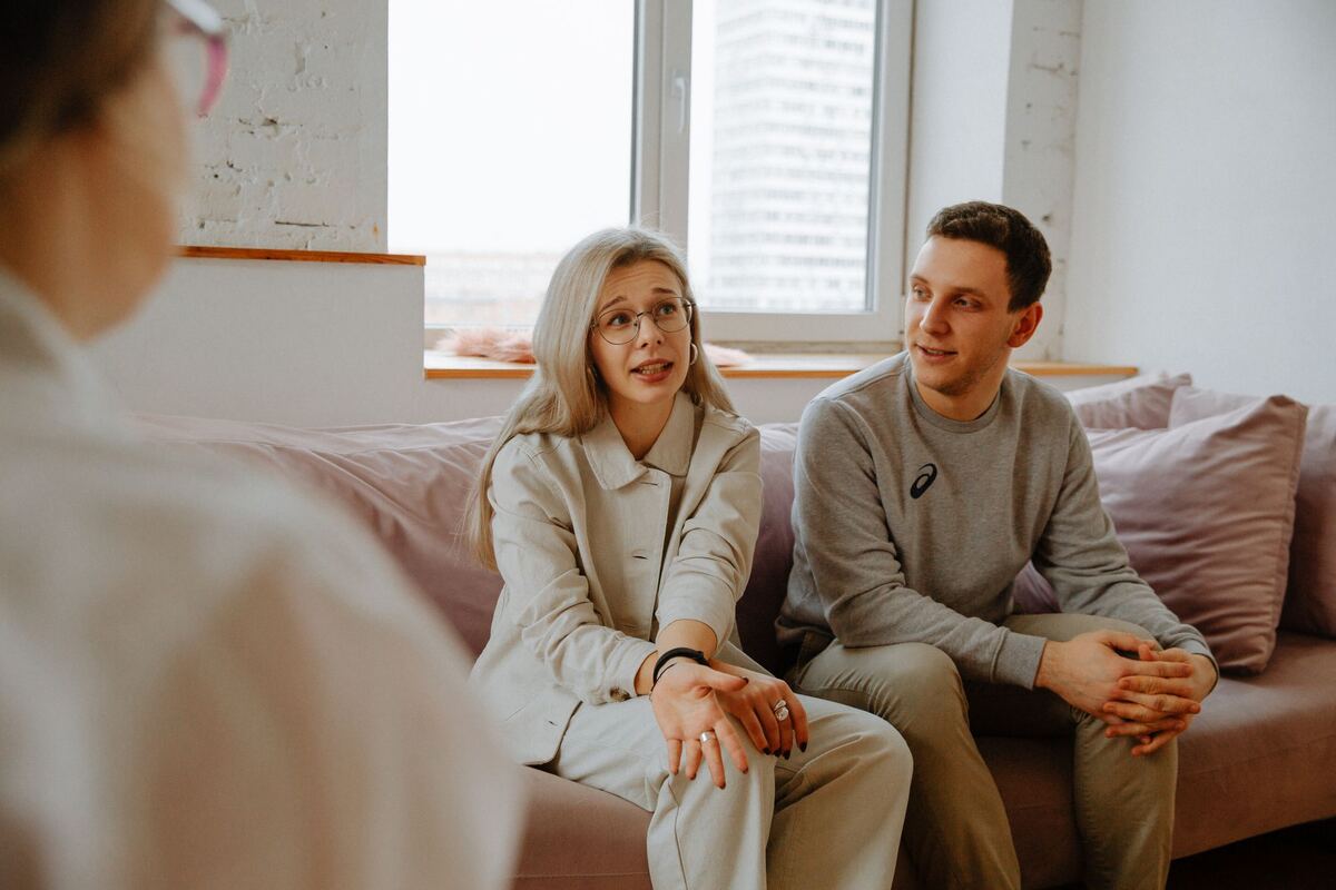 Two clients sitting together in a session with a therapist, mid conversation