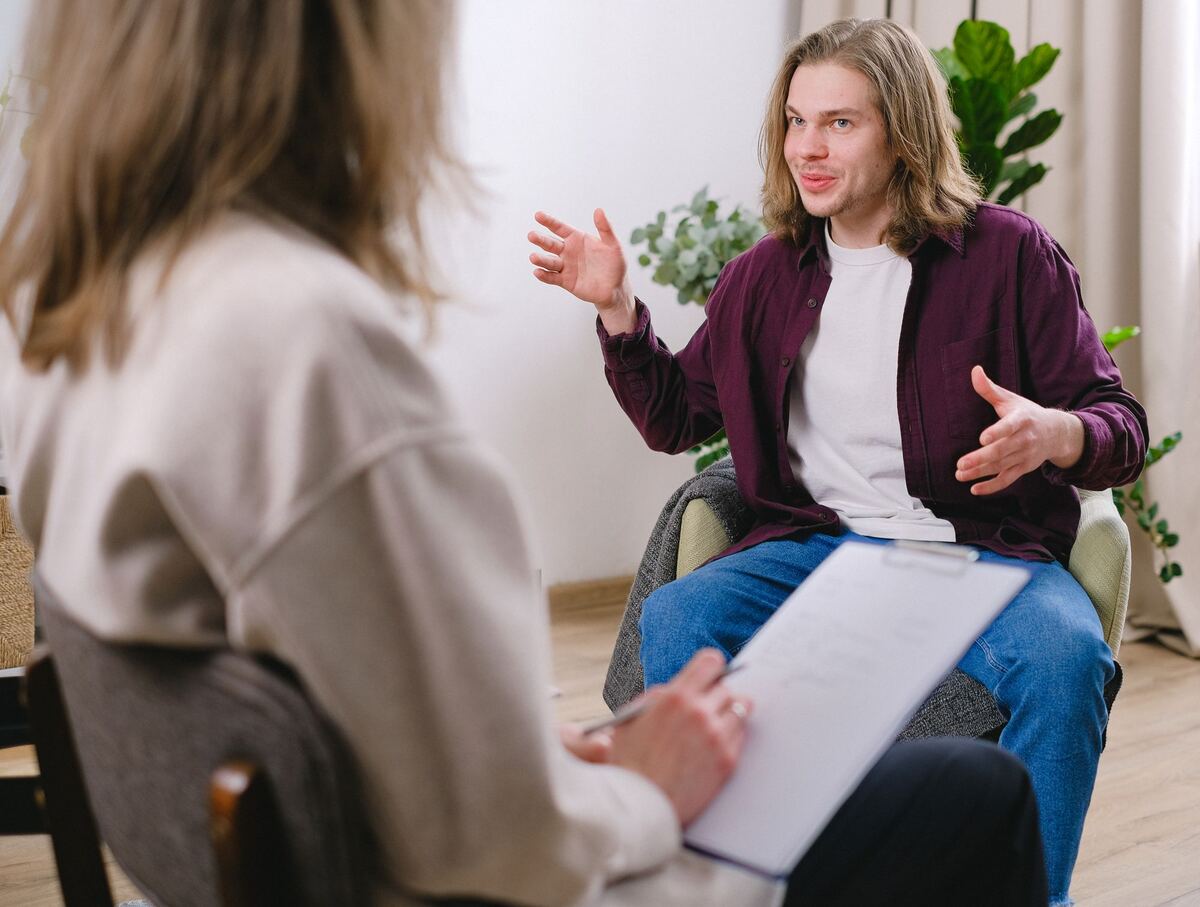 A person in conversation with a counsellor who is listening attentively in a quiet consulting room