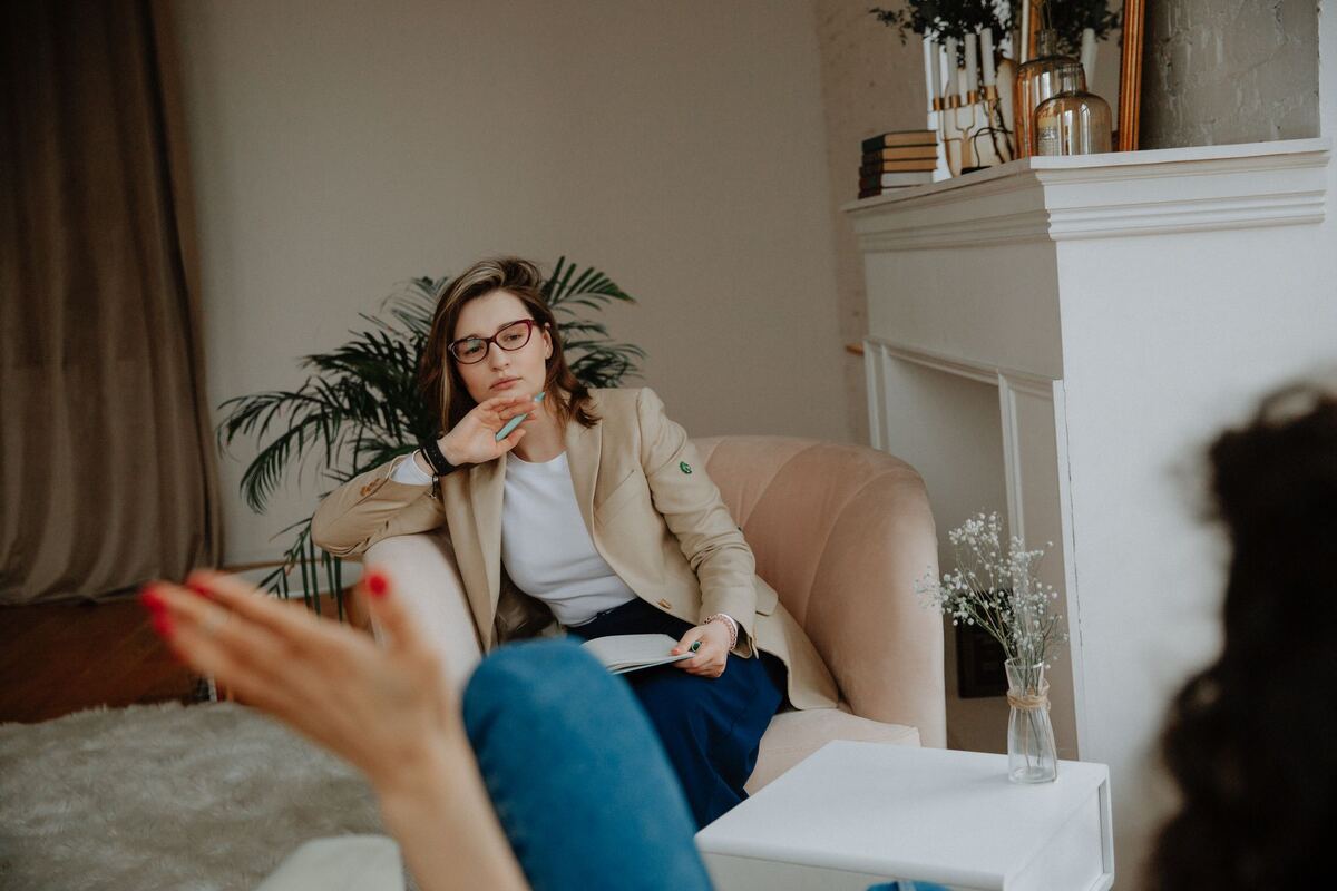 A counsellor making brief notes while a client speaks during a session