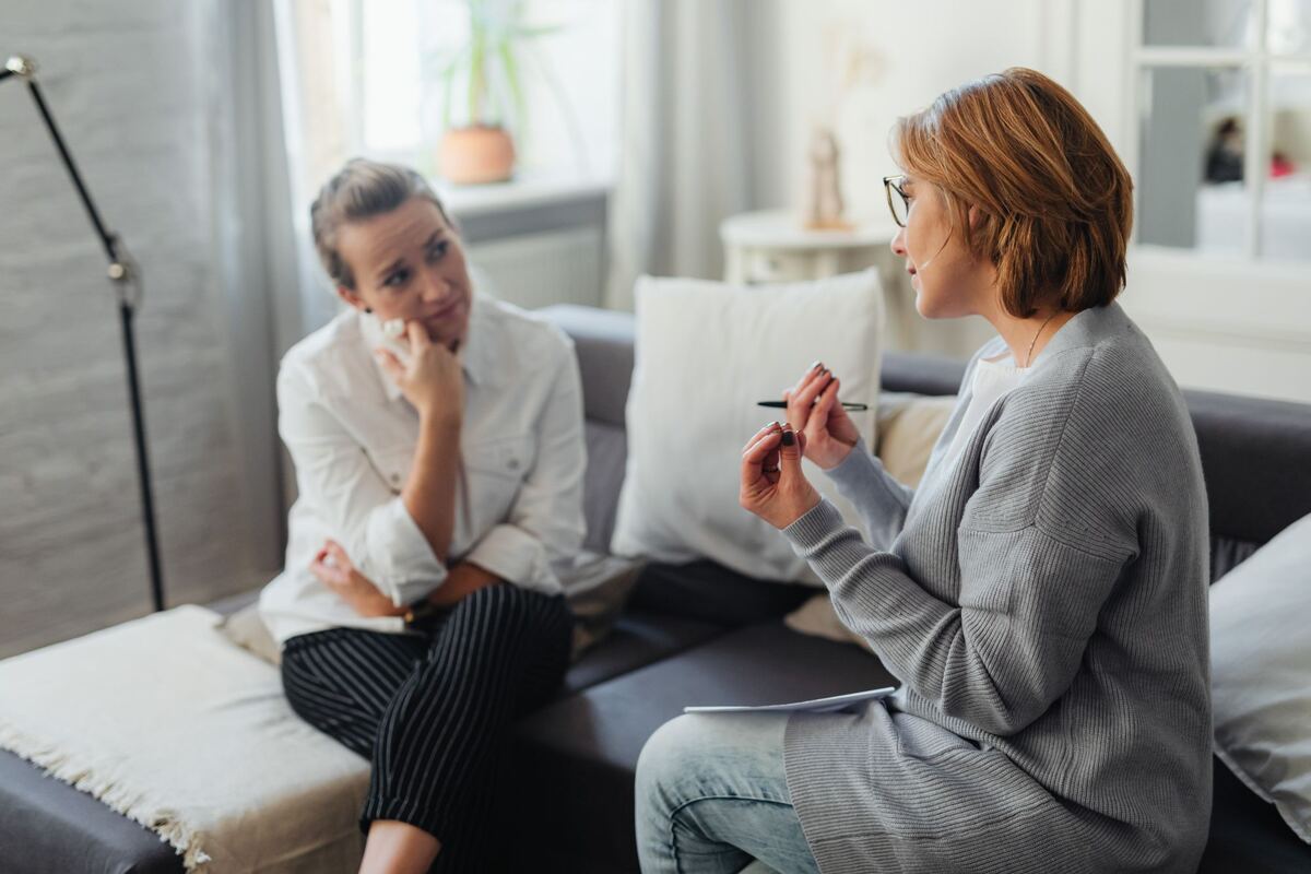 Two people seated facing each other in a bright consulting room during a counselling session